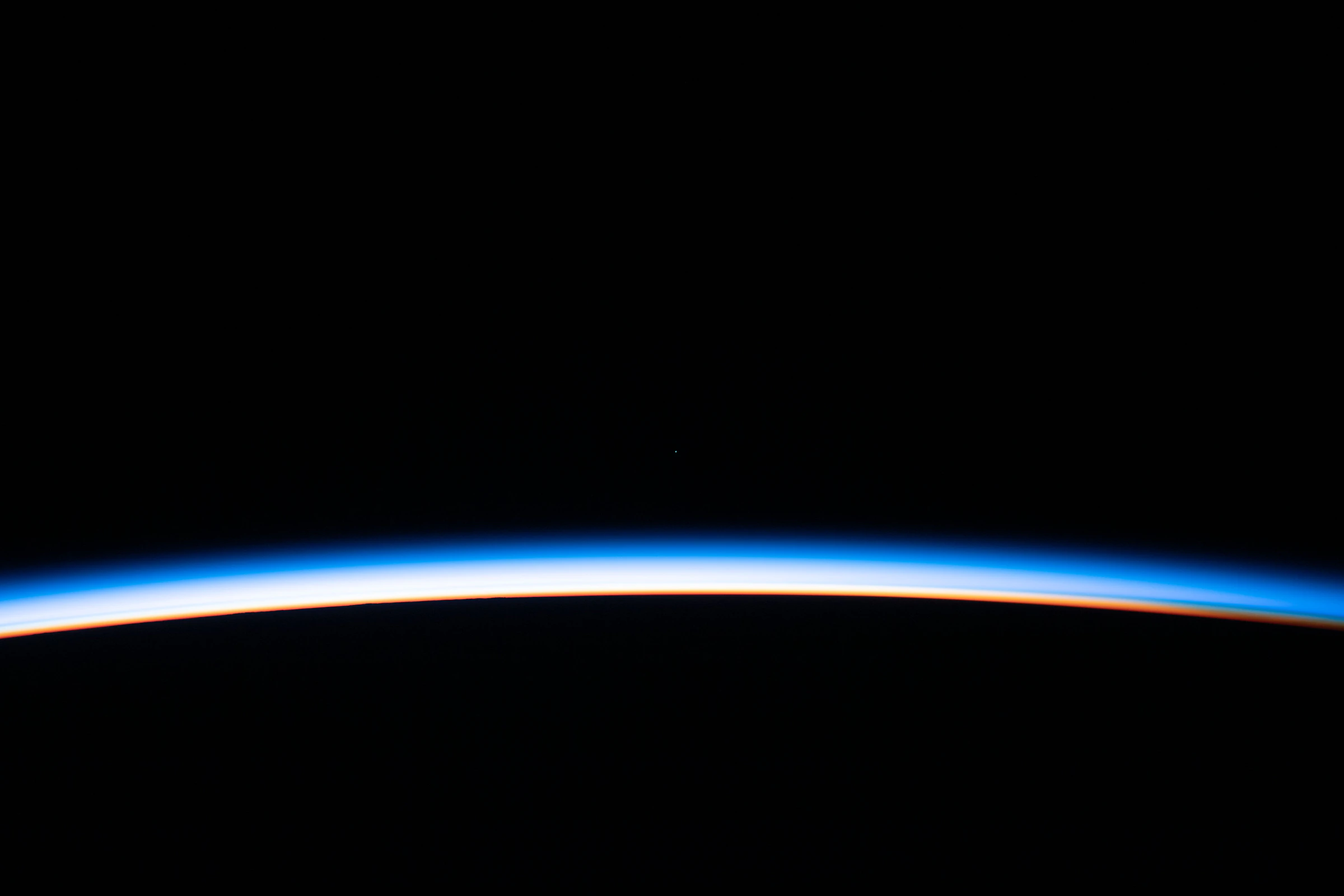 The thin line of Earth's atmosphere at orbital sunrise, photographed from the International Space Station